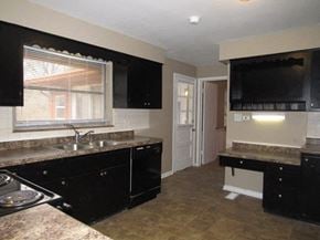 Indianapolis house for rent - A kitchen with black cabinets and a granite countertop.