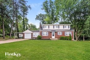 Florissant house for rent - a brick house with a green lawn and a white garage