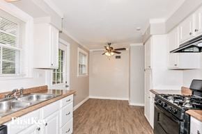 Florissant house for rent - a kitchen with white cabinets and a stove and a ceiling fan