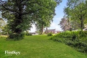 Florissant house for rent - a green field with trees and a house in the background