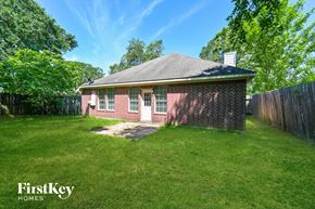 Spring house for rent - A small house with a white door and a chimney is surrounded by a fence and green grass.