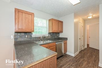 Ellenwood house for rent - a kitchen with wood cabinets and granite counter tops and a sink