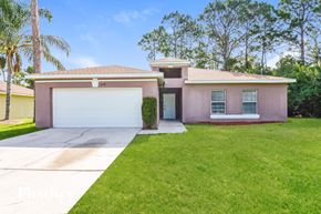 North Port house for rent - a pink house with a driveway and a garage door