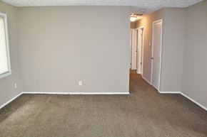 Brownsburg house for rent - an empty room with a carpeted hallway and a door to a bedroom