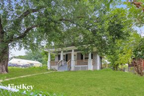 Kansas City house for rent - A house with a porch is surrounded by trees.