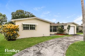 Lauderhill house for rent - A house with a driveway and a tree in front of it.