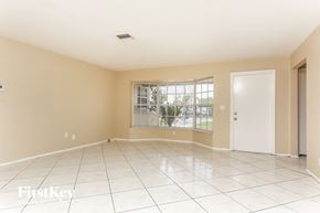 Lauderhill house for rent - A spacious room with a white door and a window.