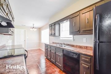 Memphis house for rent - A kitchen with brown cabinets and a black refrigerator.