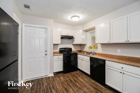Jacksonville house for rent - a kitchen with white cabinets and black appliances