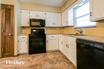 Blue Springs house for rent - a kitchen with white cabinets and black appliances