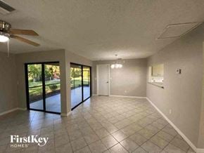 Cape Coral house for rent - A spacious room with a ceiling fan and sliding glass doors leading to a garden.