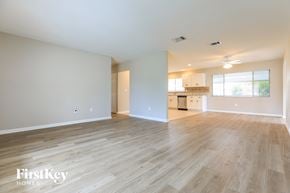 North Port house for rent - A spacious room with wooden flooring and a kitchen area in the background.