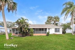 North Port house for rent - A house with a lawn and palm trees in front of it.