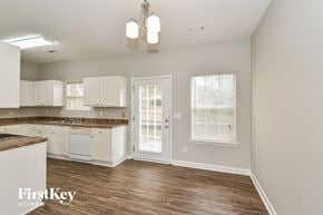 Union City house for rent - an empty kitchen with white cabinets and a door to the living room