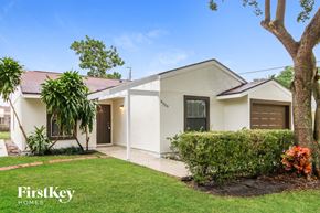 West Palm Beach house for rent - A white house with a red roof and a tree in front.