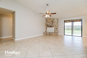 West Palm Beach house for rent - A spacious room with a fan and a stone fireplace.