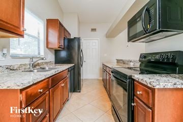 West Palm Beach house for rent - A kitchen with a black fridge and black oven.