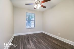 West Palm Beach house for rent - A room with a ceiling fan and a window with a view of trees.