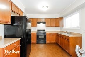 Chicago house for rent - a kitchen with wooden cabinets and black appliances