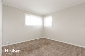 Chicago house for rent - a bedroom with a carpet and two windows