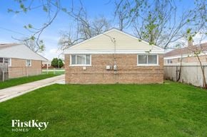 Chicago house for rent - the backyard of a brick house with green grass and a sidewalk