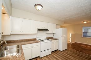 Indianapolis house for rent - A kitchen with white cabinets and a stove top oven.