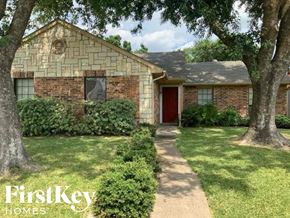 Rowlett house for rent - A brick house with a red door and a tree in front.