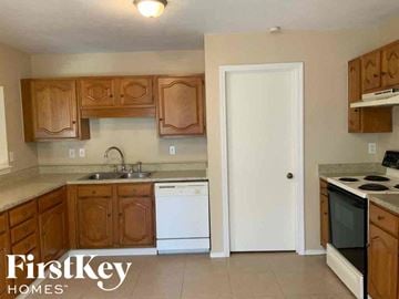 Rowlett house for rent - A kitchen with wooden cabinets and a white door.