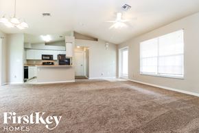 Lehigh Acres house for rent - an empty living room with carpet and a kitchen