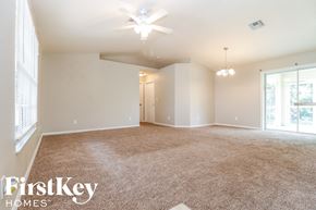 Lehigh Acres house for rent - a spacious living room with carpet and a ceiling fan