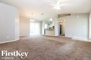 Lehigh Acres house for rent - an empty living room with carpet and a ceiling fan
