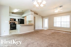 Lehigh Acres house for rent - an empty living room with a kitchen in the corner
