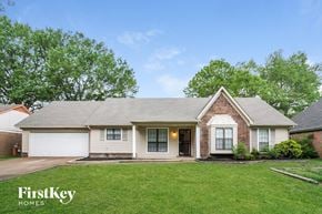 Memphis house for rent - front view of a white and brick house with green grass and trees