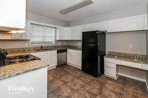 Memphis house for rent - a kitchen with white cabinets and granite counter tops and a black refrigerator