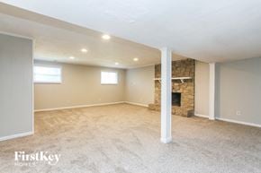Indianapolis house for rent - A spacious room with a stone fireplace and carpeted floor.