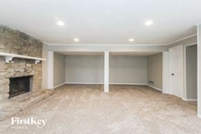 Indianapolis house for rent - A spacious room with a stone fireplace and carpeted floor.