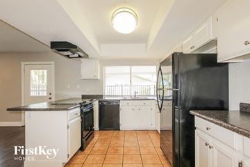 Glendale house for rent - a kitchen with white cabinets and black appliances and a window