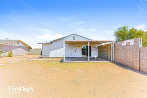 Phoenix house for rent - A house with a white exterior and a brown fence is for sale.