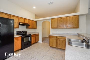 Kissimmee house for rent - A kitchen with wooden cabinets and a black fridge.
