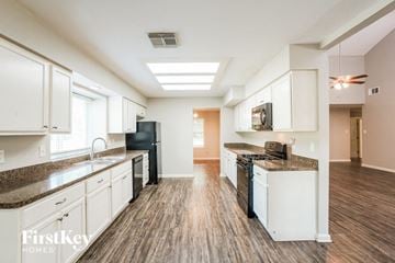 Houston house for rent - A kitchen with white cabinets and a black fridge.