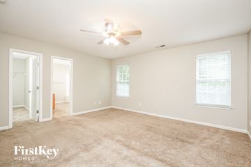 Greensboro house for rent - a spacious living room with carpet and a ceiling fan