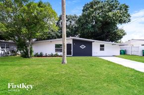 Tampa house for rent - a white and blue house with a yard and a tree