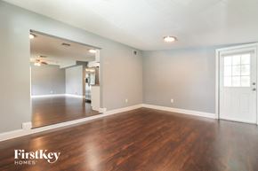 Tampa house for rent - the living room and dining room with wood flooring and a white door