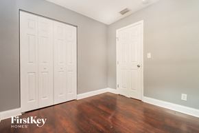 Tampa house for rent - a bedroom with two closets and wooden floors and two white doors