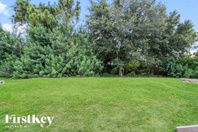 Lehigh Acres house for rent - A lush green lawn with trees in the background and a bench on the left side.