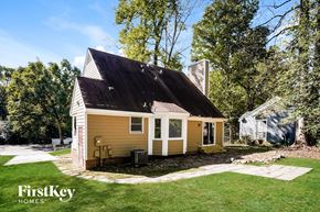 Knightdale house for rent - A small house with a porch is surrounded by a grassy yard.
