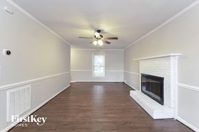 Knightdale house for rent - A spacious room with a fireplace and a ceiling fan.
