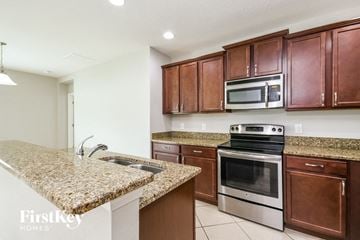 Kissimmee house for rent - a kitchen with granite counter tops and wooden cabinets