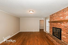 Memphis house for rent - A room with a brick fireplace and wood flooring.