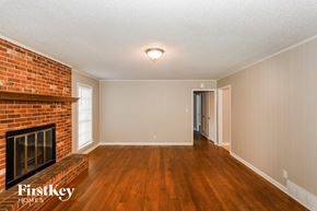 Memphis house for rent - A room with a brick fireplace and wooden floors.
